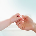 Baby holding adult hand representing new life